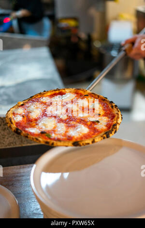 Close-up di pizzaiolo con pizza preparata su pizza peel Foto Stock
