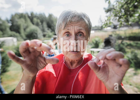 Ritratto di donna senior gesticolando in giardino Foto Stock