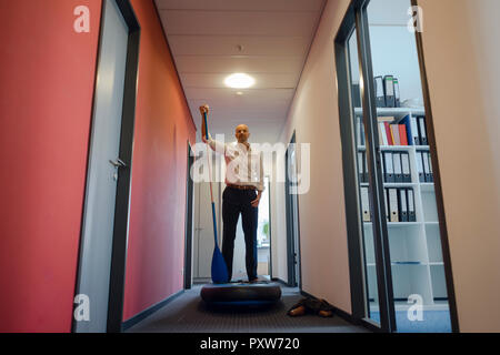 Imprenditore permanente sulla scheda paddle, esercitando nel corridoio di office Foto Stock