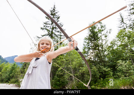 Ragazza sorridente mirando con arco e frecce nella natura Foto Stock