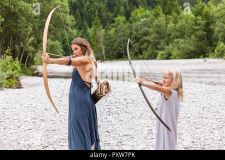 Madre e figlia mirando con arco e frecce nella natura Foto Stock