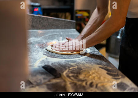 Close-up di pizzaiolo preparare pasta della pizza in cucina Foto Stock