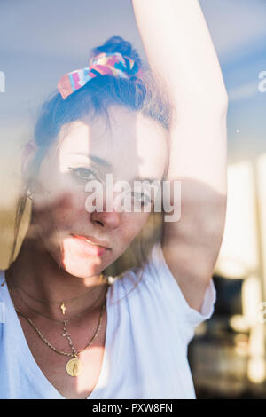 Ritratto di giovane donna dietro il vetro di finestra Foto Stock