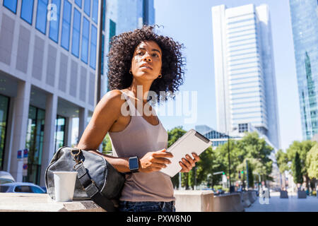 Germania, Francoforte, Ritratto di giovane donna con borsa da viaggio, tablet e caffè per andare in città Foto Stock
