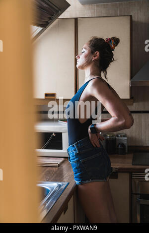Giovane donna in piedi in cucina a casa Foto Stock