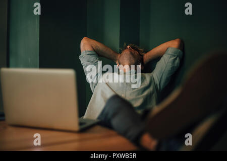 Stanco uomo seduto in ufficio, lavora fino a tardi nella sua azienda start-up Foto Stock