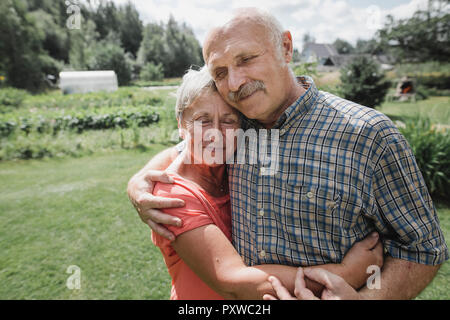 Ritratto di felice coppia senior che abbraccia ogni altra in giardino Foto Stock