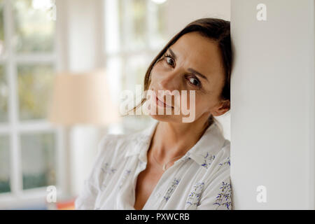 Ritratto di donna matura appoggiata contro il telaio di porta Foto Stock