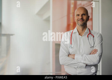 Dottore in piedi in ospedale con uno stetoscopio intorno al suo collo Foto Stock