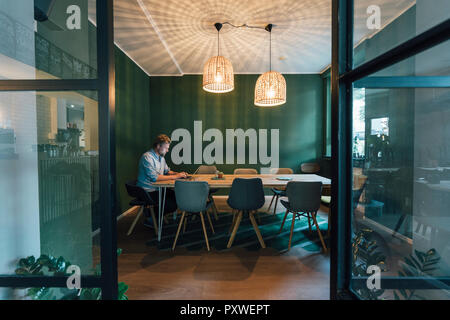 Uomo seduto in ufficio, lavora fino a tardi nella sua azienda start-up Foto Stock