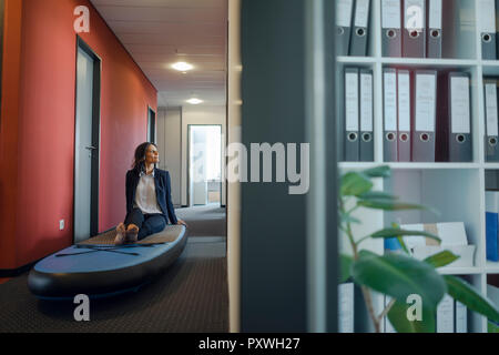 Imprenditrice seduta sulla scheda paddle, fantasticando in office Foto Stock