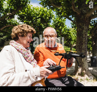 Coppia senior giocando con un drone in posizione di parcheggio Foto Stock