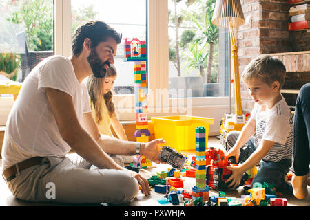 La famiglia gioca con la costruzione di blocchi sul pavimento insieme Foto Stock