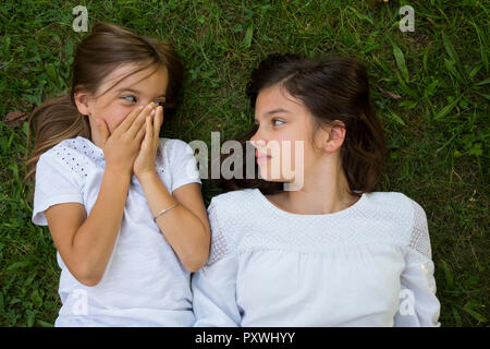 Due sorelle insieme sdraiati su un prato Foto Stock