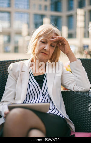 Senior imprenditrice è seduta in cafe e la ricerca di lavoro su internet. Foto Stock