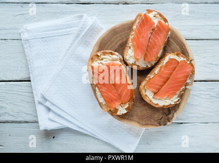 Vista superiore a sandwich con salmone affumicato e crema di formaggio su un bianco tavolo in legno Foto Stock