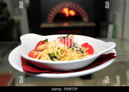 Linguine con polpa di granchio con Rucola e Pomodorini e peperoncino, finito con olio d'oliva in un ristorante di impostazione Foto Stock