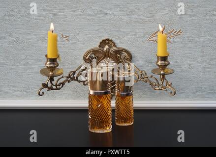 Diva, fragranza per signore, grande bottiglia di profumo accanto a un profumo commerciale la bottiglia nella parte anteriore di un pianoforte candelabri con brillanti candele Foto Stock