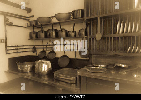 Seppia immagine atemporale di parte di una cucina in stile vittoriano con rame puro padelle, pentole, scaffalature e la piastra del rack. Foto Stock