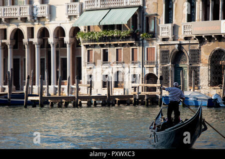 Un gondoliere sul Grand Canal puntando qualcosa fuori per due passeggeri nella sua gondola. Foto Stock
