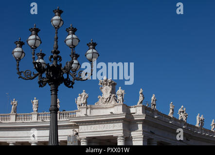 Un lampione e il colonnato di Piazza San Pietro nella Città del Vaticano, che mostra la curva della trabeazione con la fila di statue di santi. Foto Stock