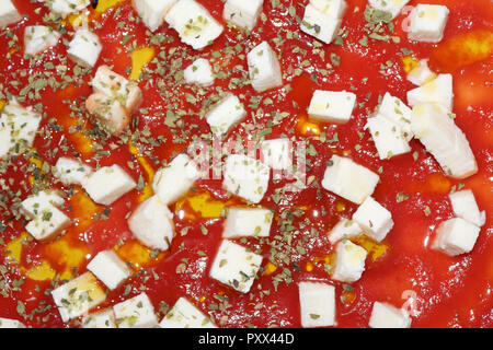 Una vista ravvicinata della pizza cruda, con pomodoro, mozzarella cubetti e origano, prima di essere cotti in un forno, tipico della cucina italiana Foto Stock