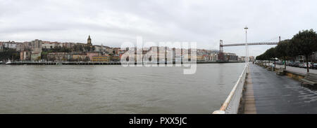 Una vista di Portugalete dalla passeggiata sul fiume, con l'antenna il Ponte di Vizcaya (Puente de Vizcaya) sul fiume Nervion in un nuvoloso giorno di inverno, Spagna Foto Stock