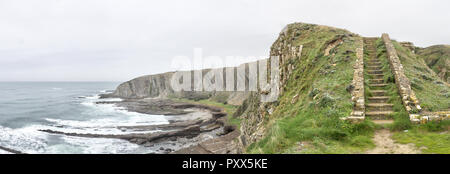 Paesaggio di scala a alte scogliere sul mare agitato durante un nuvoloso giorno di pioggia da Paseo de la Galea nella città di Getxo, nei Paesi Baschi, Spagna Foto Stock