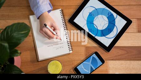 Composizione digitale della tavoletta digitale e telefono cellulare sul tavolo con la scrittura a mano su notebook Foto Stock