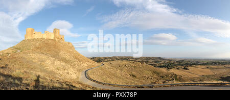 Un paesaggio del medievale abbandonato Montearagon castello posto su di una collina tra arati campi di raccolto, in un pomeriggio d'estate, nella regione di Aragona, Spagna Foto Stock