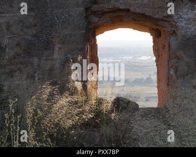 La coltivarono campi di raccolto della regione di Aragona visto da una rovina finestre in pietra della abbandonato Montearagon castello, durante il tramonto, in Spagna Foto Stock