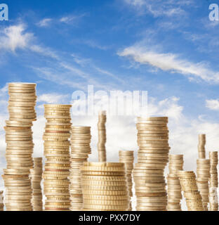 Alte torri di monete che rappresenta la ricchezza sotto un cielo blu Foto Stock