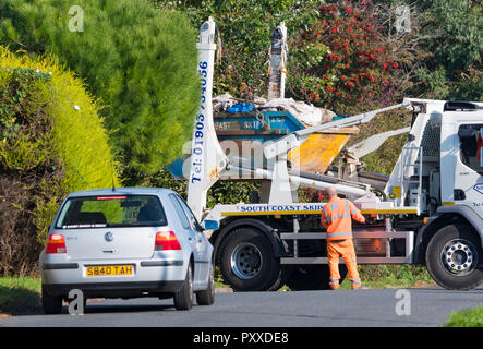 Carrello consegnando, lo scarico o il prelievo di un edificio saltare piena di edificio o rifiuti di costruzione di una zona residenziale nel Regno Unito. Foto Stock