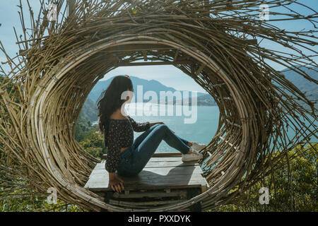 Donna seduta su un legno sulla cima della montagna Foto Stock