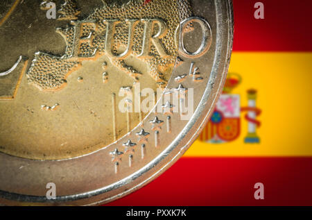 2 monete in euro con una offuscata bandiera della Spagna sullo sfondo. Foto Stock