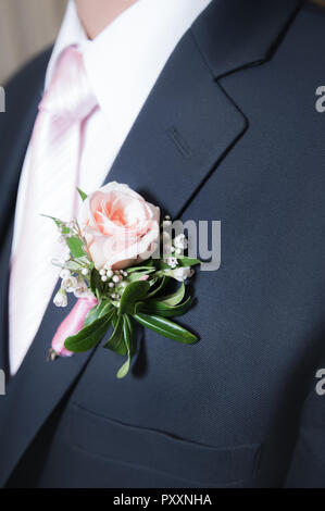 Una rosa rosa boutonniere su un uomo navy giacca. Foto Stock