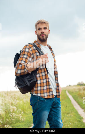 Ritratto di bello pensieroso uomo nero con zaino in pelle che guarda lontano nel campo Foto Stock