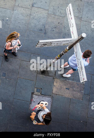 Birds Eye view su pedoni utilizzando i telefoni cellulari accanto al cartello stradale Foto Stock