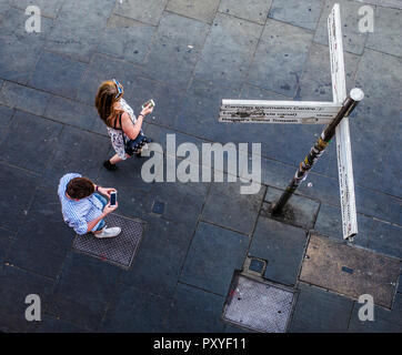 Birds Eye view su pedoni utilizzando i telefoni cellulari accanto al cartello stradale Foto Stock
