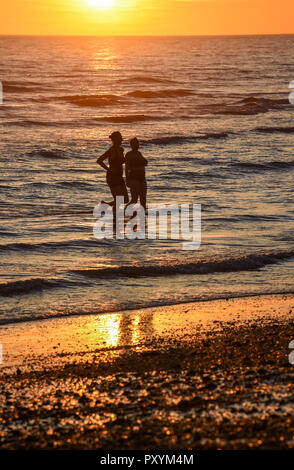 Brighton, Regno Unito. 24 ott 2018. Nuotatori godetevi un fine tuffo in mare come il sole tramonta dal Molo Ovest di Brighton questa sera dopo un altro giorno caldo e soleggiato sulla costa sud Credito: Simon Dack/Alamy Live News Foto Stock