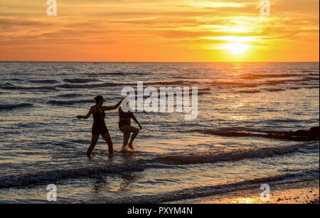 Brighton, Regno Unito. 24 ott 2018. Nuotatori godetevi un fine tuffo in mare come il sole tramonta dal Molo Ovest di Brighton questa sera dopo un altro giorno caldo e soleggiato sulla costa sud Credito: Simon Dack/Alamy Live News Foto Stock