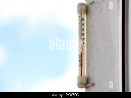 Alcool tradizionale termometro di vetro Celsius attaccata alla parete intonacata al di fuori che mostra la temperatura fredda sulla luminosa luce sfocata colorato all'aperto co Foto Stock