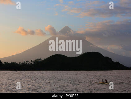Vulcano Mayon e persone in outrigger nel lago al tramonto, Legazpi City, provincia di Albay, Filippine Foto Stock