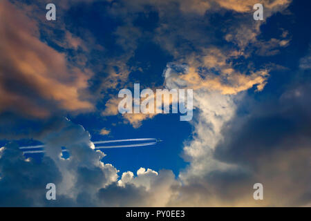 Vista in lontananza aereo commerciale volare nel cielo e lasciando il sentiero di vapore dietro Foto Stock