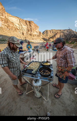 Due uomini pasto di cottura in cucina esterna durante il viaggio rafting, desolazione/Grigio sezione del canyon, Utah, Stati Uniti d'America Foto Stock