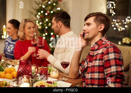 L'uomo chiamando sullo smartphone a cena di natale Foto Stock