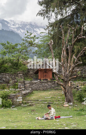 Un uomo che fa l'artigianato su un prato in un piccolo indiano villaggio di montagna Foto Stock