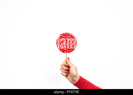 Rosso e bianco lecca-lecca a spirale in mano donna isolato su sfondo bianco. Ragazze holding hard candy cane caramello su stick, dolci vacanze concetto, cop Foto Stock