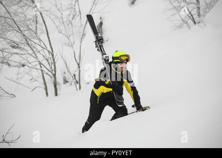 Sorridenti sciatore passeggiate in montagna nella neve profonda dopo freeride sci alpino con sci in spalla Foto Stock