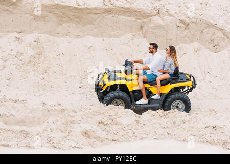 Sorridente coppia giovane riding veicolo fuoristrada nel deserto Foto Stock